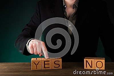 Businessman Pointing at Wood cube block with word â€œYESâ€ on Black Background. YES and NO. Decision Making. Stock Photo